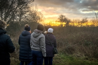 A group of adults watch the sunrise