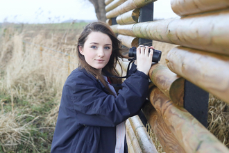 Young woman holding binoculars at a wetland nature reserve
