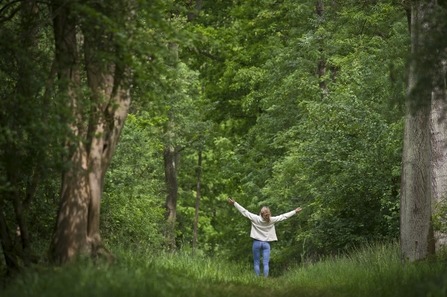 Woman in a wood with arms outstretched above her