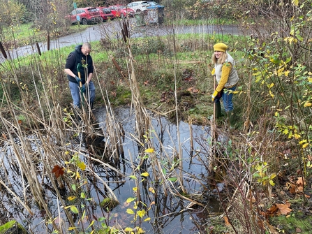 Two volunteers clearing a pond