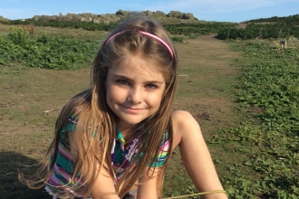 Grace sits in the grass with flowers