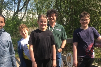 Teenagers stood on a bridge with a member of BBOWT staff