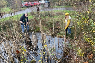 Two volunteers clearing a pond