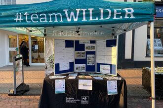 Photographic image of a BBOWT Team Wilder gazebo, with information boards on a table beneath.
