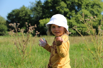A little girl holds an insect tub in a field of long grass. Picture Lianne de Mello