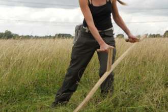 A lady scything long grass