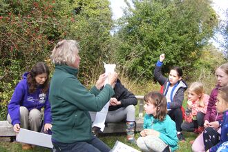 Young rangers gather round a leader at a camp