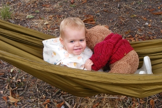 A child sits in hammock with their teddy bear