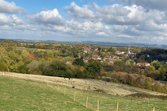 View across fields and woods to housing in a valley