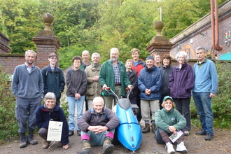 A group of volunteers standing in front of a brick wall and trees