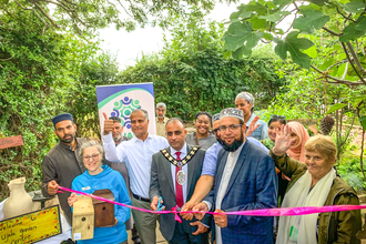 Mayor of Slough Amjad Abbasi cuts the ribbon on the new garden at the Ujala Foundation community centre, with BBOWT Community Wildlife Officer Barbara Polonara left, in blue.