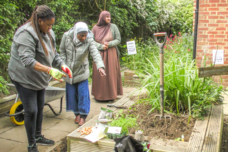 Members of the Slough Ujala Foundation community help create a garden at Manor Park Pavilion. Picture: Pete Hughes