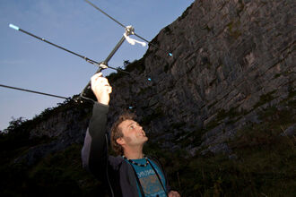 A researcher holding bat detecting equipment at twilight