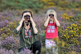 Family look straight at the camera through binoculars