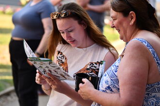 A close-up image of two people looking at a bird identification guide.
