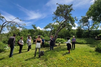 Group of people in a green space listening to a talk