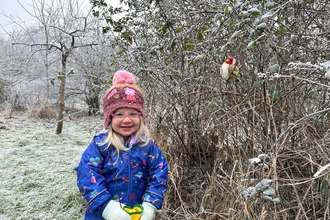 A smiling child next to a frosty hedge