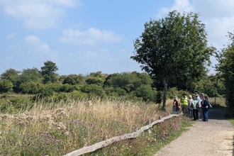 a group of adults on a track beside a tree and grass