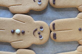 Close-up image of a tray of gingerbread-people biscuits with piped icing decorations