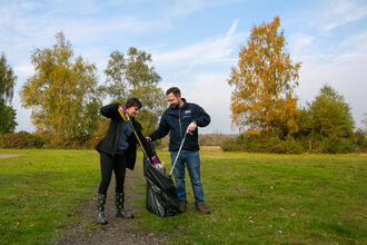 Two people litter picking in a park