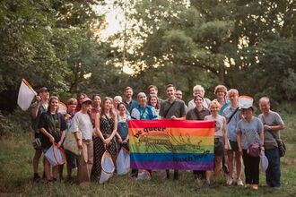 A group of people with bug nets with a pride flag.