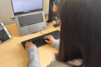 Person working at a computer with hands on remote keyboard