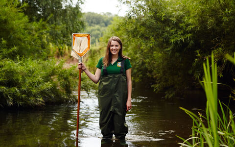 Sophie standing in a river with a net