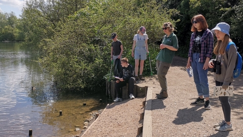 Teenagers and a member of BBOWT staff looking out over the water at the Nature Discovery Centre