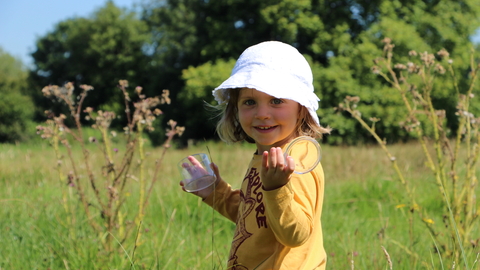A little girl holds an insect tub in a field of long grass. Picture Lianne de Mello