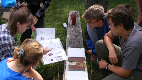 a group of teenagers look at footprints and a key