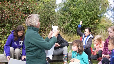 Young rangers gather round a leader at a camp