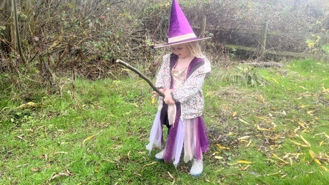 girl in a purple witch costume standing on grass