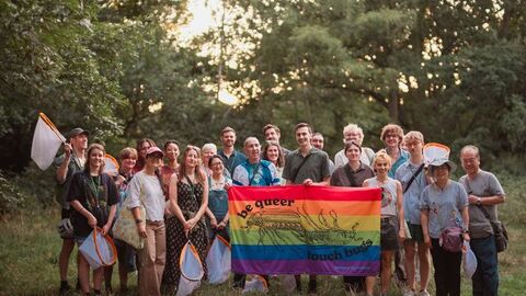 A group of people with bug nets with a pride flag.