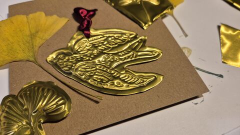 Image of the results of a metal embossing workshop. An intricate design of a bird is inlaid into a gold plate.