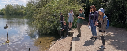 Teenagers and a member of BBOWT staff looking out over the water at the Nature Discovery Centre