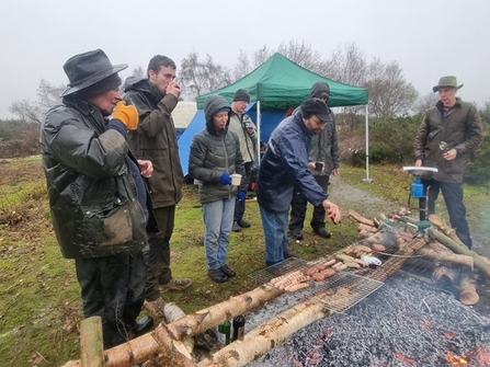 People standing around a barbecue in the rain