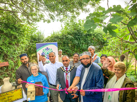 Mayor of Slough Amjad Abbasi cuts the ribbon on the new garden at the Ujala Foundation community centre, with BBOWT Community Wildlife Officer Barbara Polonara left, in blue.