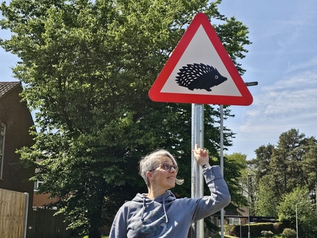 Barbara pointing to a hedgehog warning road sign