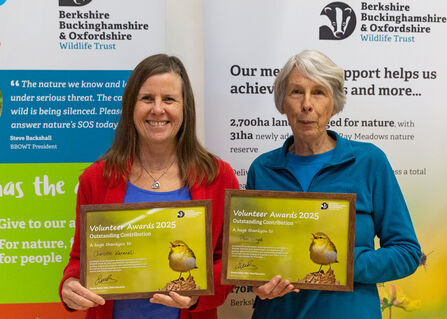 Two women smiling at the camera, holding their framed awards.