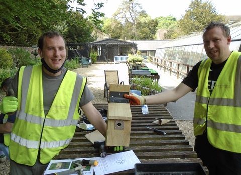Two people holding a bird nest box