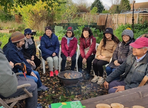 Members of the Hong Kong Community in Southcote, Reading enjoying a fireside chat outdoors