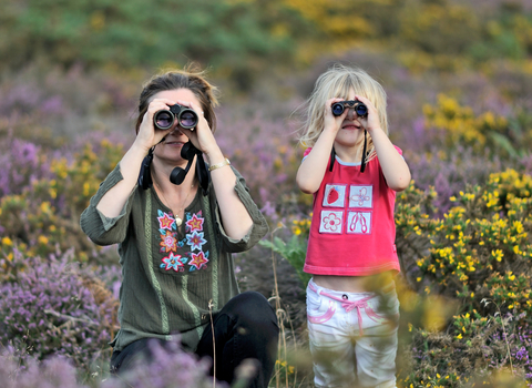 Family look straight at the camera through binoculars