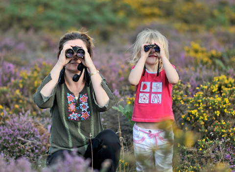 Family look straight at the camera through binoculars