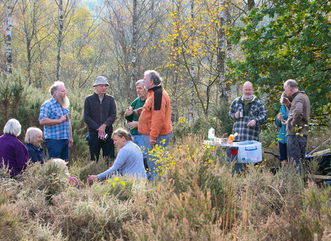 Volunteer work party in a woodland, socialising during a break